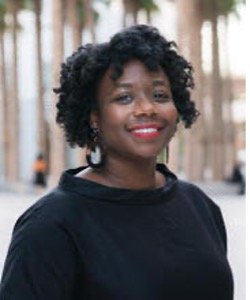Portrait of a person with curly hair smiling outdoors